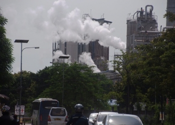Kepulan asap keluar dari cerobong salah satu pabrik yang berada di Jalan Raya Anyer, Kota Cilegon.