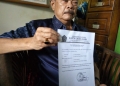 Saudagar beras asal Pandeglang, H Ating Saefudin saat memperlihatkan surat keterangan dari KUA Menes.
