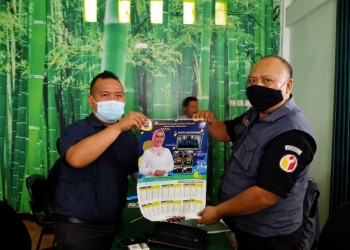 Tim Advokasi Nasrul Ulum-Eki Baihaki (ASIK) memperlihatkan kalender yang terdapat foto Pasangan Calon (Paslon) nomor urut satu, Tatu - Pandji yang diduga dibagikan oleh BUMD PDAM Tirta Albantani.