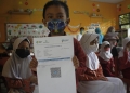 Salah seorang pelajar Sekolah Dasar (SD) di wilayah Kota Cilegon, saat menunjukan printan kartu vaksinasi Covid-19, usai dilakukan vaksinasi yang digelar Polda Banten, di SD Negeri Bujanggadung Jalan Grogol Rawaaum, Kecamatan Grogol, Kota Cilegon, Banten,  Rabu (19/1).   RULIE SATRIA/BANTEN POS