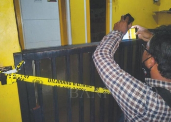 Tempat kejadian perkara pembunuhan dipasangi garis polisi.