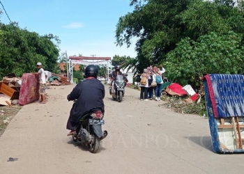 Sekelompok masyarakat sedang berswafoto bersama di dekat jembatan Keganteran, Kelurahan Kasemen, Kota Serang, Kamis (3/3). Terlihat kelompok masyarakat tersebut tengah berswafoto saat penyintas bencana banjir sedang membersihkan kasurnya yang basah akibat terendam banjir. (Diebaj/BantenPos)