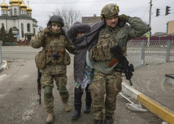 Pasukan Ukraina membantu seorang wanita, di kota Irpin, Ukraina, 6 Maret 2022