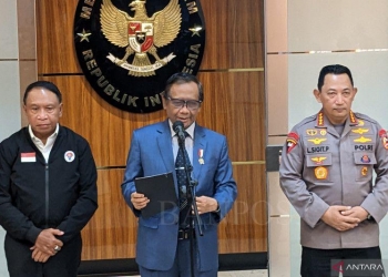 Menkopolhukam Mahfud MD (tengah) didampingi Menpora Zainudin Amali (kiri) dan Kapolri Jenderal Polisi Listyo Sigit Prabowo memberikan pernyataan soal lanjutan Liga 1, 2 dan 3 Indonesia musim 2022-2023 di Kantor Kemenpolhukam, Jakarta, Senin (5/12/2022). (ANTARA/Michael Siahaan)