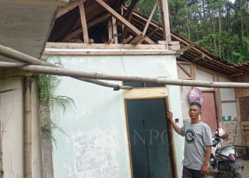 Salah satu warga korban pergerakan tanah merobohkan rumahnya yang telah rusak berat.