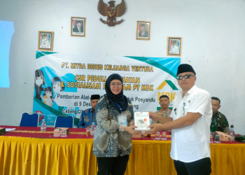Asisten Regional Manager PT MBK, Resma Nurani saat menyerahkan bantuan secara simbolis kepada Camat Cibaliung, Hadi Patoni.