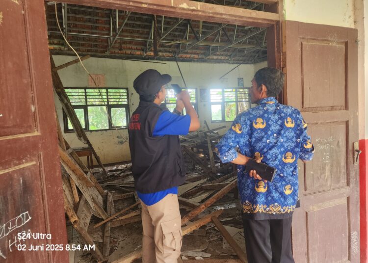 Salah seorang guru saat melihat kondisi ruang kelas yang ambruk.